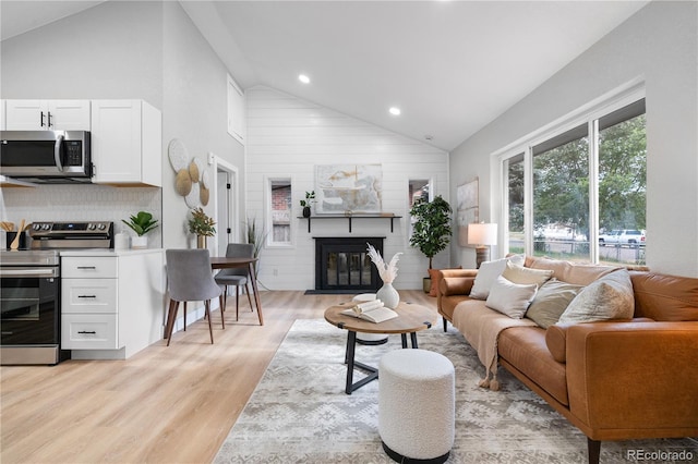 living room with high vaulted ceiling and light hardwood / wood-style floors