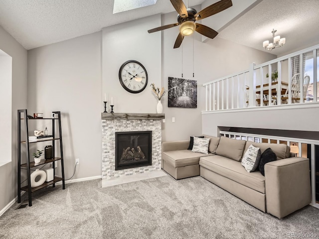 living room with vaulted ceiling with skylight, a fireplace, a textured ceiling, and ceiling fan with notable chandelier