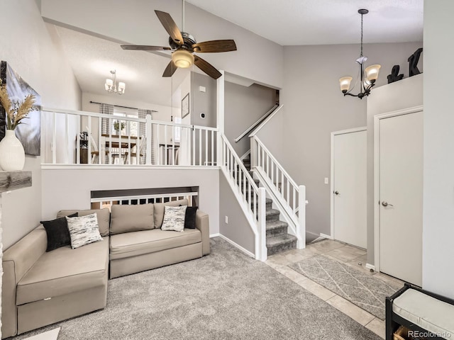 carpeted living room with high vaulted ceiling and ceiling fan with notable chandelier