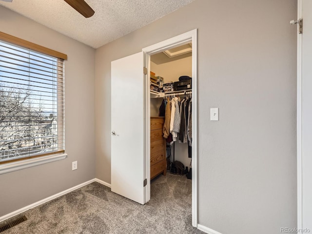 unfurnished bedroom with a spacious closet, ceiling fan, a textured ceiling, a closet, and carpet