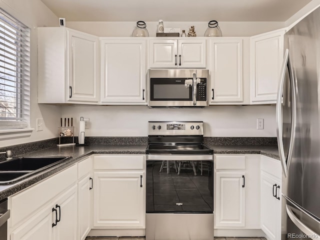 kitchen with tile patterned floors, sink, white cabinetry, and stainless steel appliances