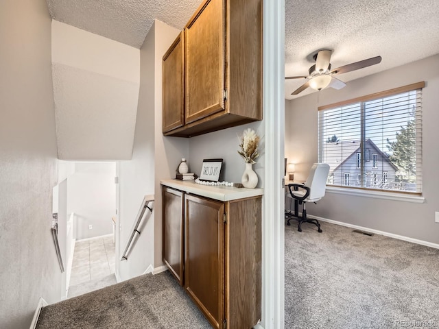 kitchen with light carpet, a textured ceiling, and ceiling fan