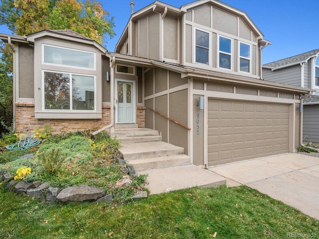 tudor-style house with stucco siding, entry steps, brick siding, a garage, and concrete driveway