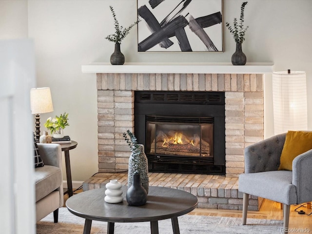room details featuring a brick fireplace, baseboards, and wood finished floors