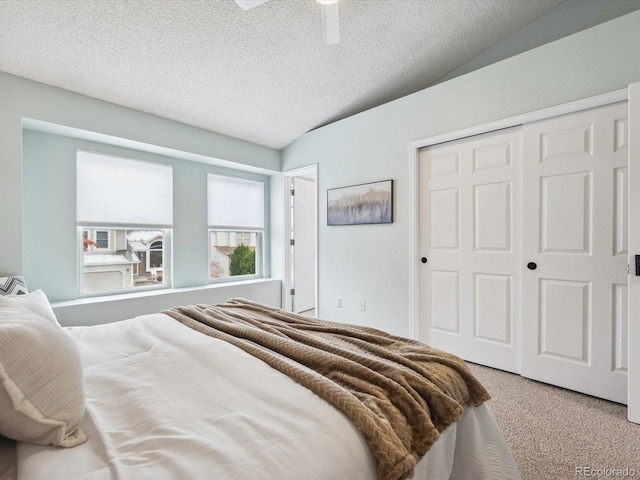 carpeted bedroom featuring a textured ceiling, a closet, a ceiling fan, and lofted ceiling