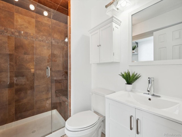 bathroom featuring toilet, vanity, and a stall shower