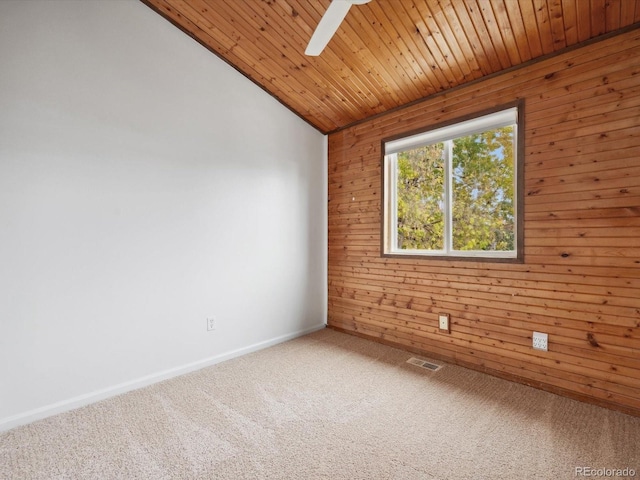 carpeted empty room with visible vents, wooden ceiling, ceiling fan, wooden walls, and vaulted ceiling