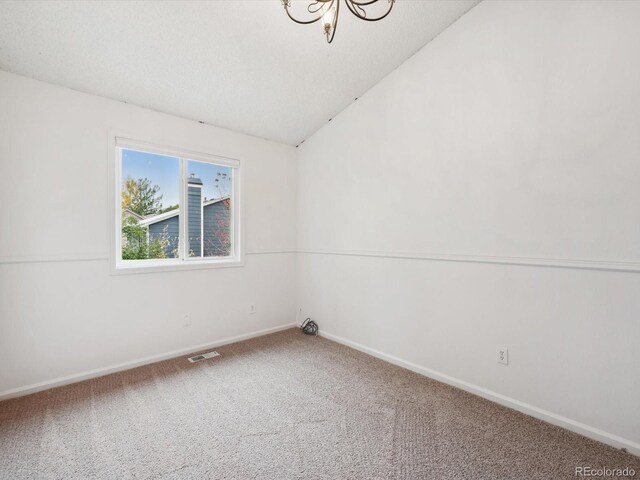 carpeted spare room with visible vents, baseboards, and lofted ceiling
