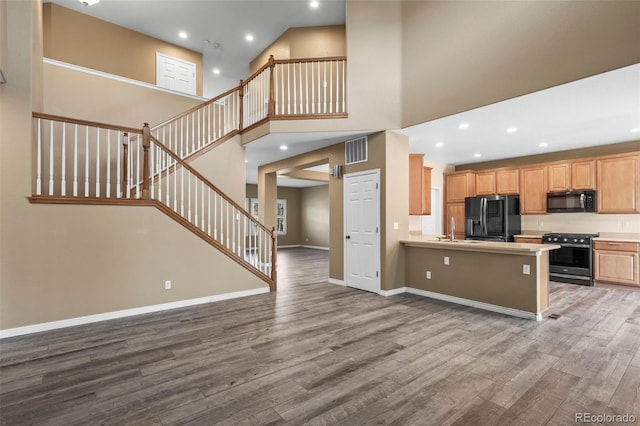 kitchen with black appliances, wood finished floors, visible vents, and baseboards