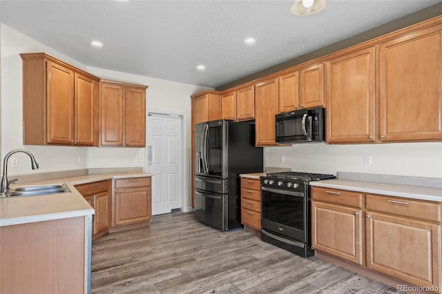 kitchen with light countertops, recessed lighting, light wood-style floors, stainless steel appliances, and a sink