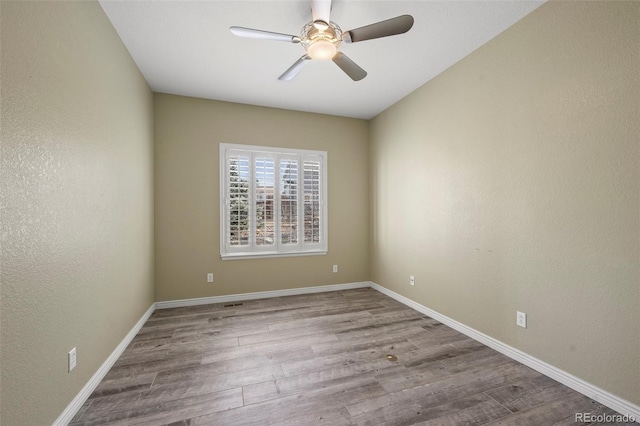 empty room featuring baseboards, wood finished floors, a ceiling fan, and a textured wall