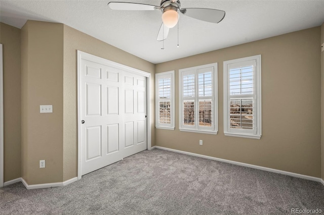 unfurnished bedroom with a closet, carpet flooring, a ceiling fan, and baseboards