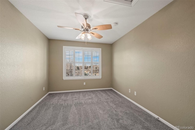 carpeted spare room featuring baseboards, attic access, a ceiling fan, and a textured wall