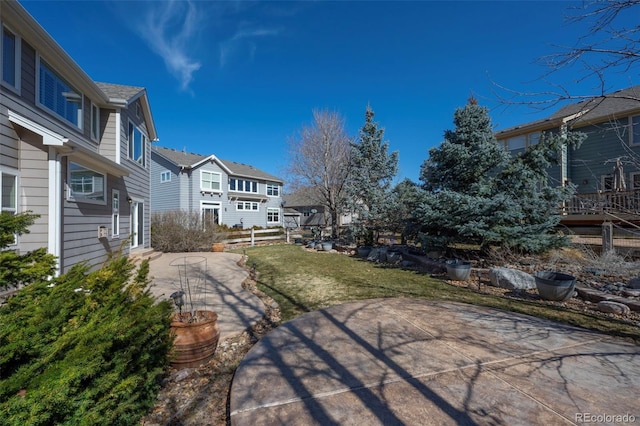 view of yard featuring a patio, fence, and a residential view