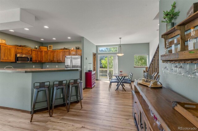 107 Mountain Vista Ln, Silverthorne, CO 80498 - kitchen featuring appliances with stainless steel finishes, brown cabinetry, light wood-style floors, a breakfast bar area, and recessed lighting