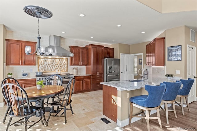 kitchen with tasteful backsplash, sink, high end appliances, kitchen peninsula, and wall chimney exhaust hood