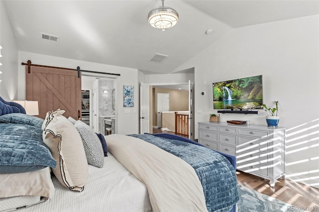 bedroom featuring vaulted ceiling, a barn door, and wood-type flooring