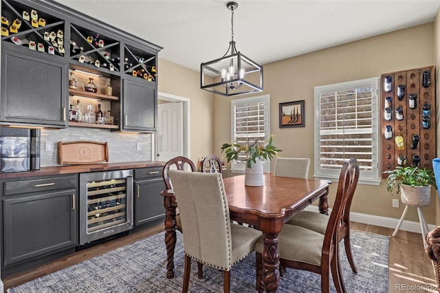 dining area with wine cooler, indoor bar, a chandelier, and dark wood-type flooring