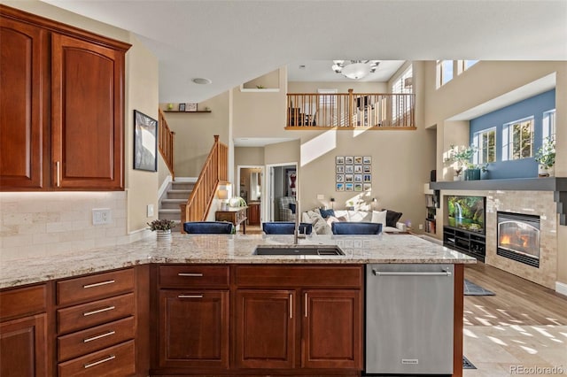 kitchen featuring sink, tasteful backsplash, kitchen peninsula, light stone countertops, and a tiled fireplace