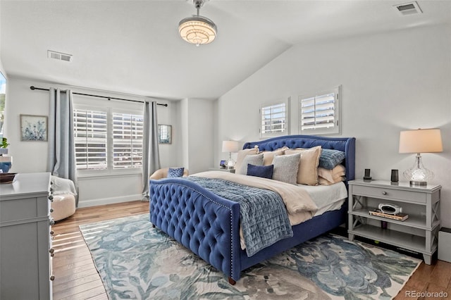 bedroom with multiple windows, lofted ceiling, and wood-type flooring