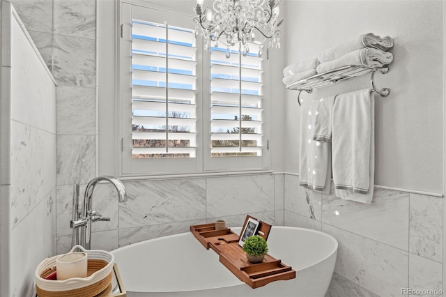 bathroom with an inviting chandelier, a bath, and tile walls