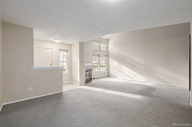 carpeted spare room with a tiled fireplace and a textured ceiling