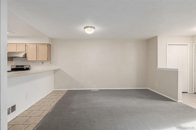 kitchen featuring electric range, a textured ceiling, and light tile patterned flooring