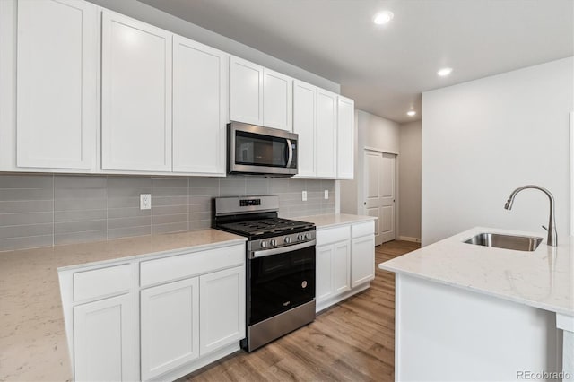 14149 Deertrack Ln, Parker, CO 80134 - kitchen with appliances with stainless steel finishes, a sink, light wood finished floors, decorative backsplash, and recessed lighting