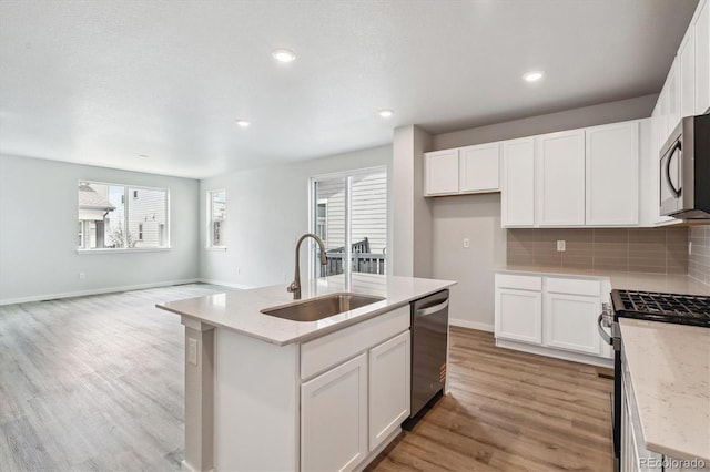 14149 Deertrack Ln, Parker, CO 80134 - kitchen featuring a sink, stainless steel appliances, light wood-style floors, an island with sink, and white cabinetry