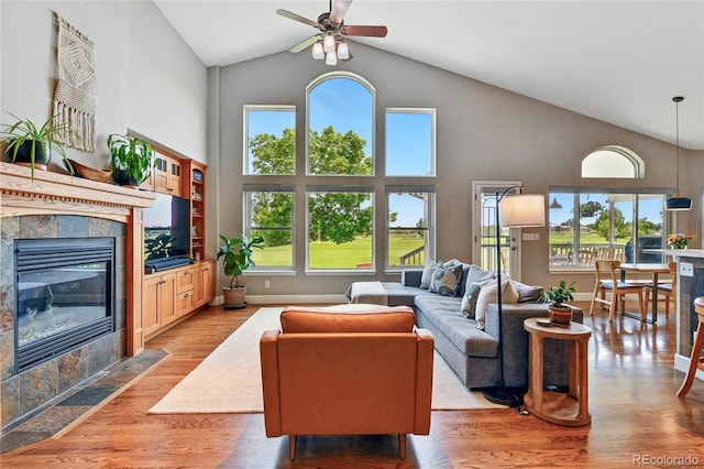 6776 Salvia Ct, Arvada, CO 80007 - living area featuring high vaulted ceiling, a ceiling fan, a tiled fireplace, and light wood-type flooring