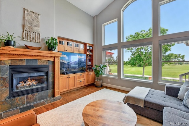6776 Salvia Ct, Arvada, CO 80007 - living area featuring high vaulted ceiling, wood finished floors, a tiled fireplace, and baseboards