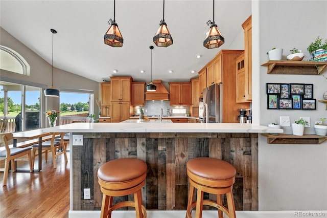 6776 Salvia Ct, Arvada, CO 80007 - kitchen with light countertops, stainless steel fridge, decorative light fixtures, backsplash, and custom exhaust hood