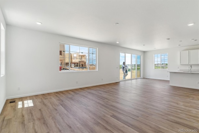459 S Salida St, Aurora, CO 80017 - unfurnished living room featuring light wood-type flooring, recessed lighting, a sink, and baseboards