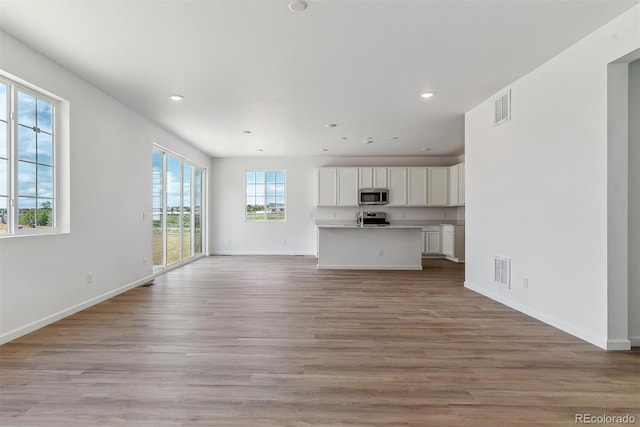 459 S Salida St, Aurora, CO 80017 - unfurnished living room with light wood-type flooring, recessed lighting, and baseboards
