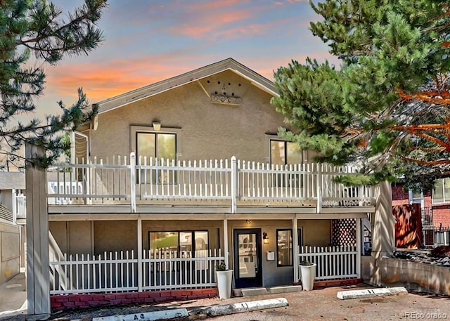 back house at dusk featuring a balcony