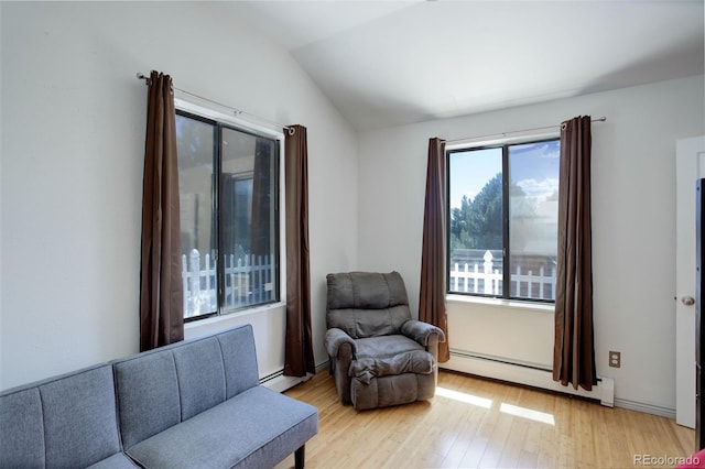 living area with a baseboard radiator, light wood-type flooring, and lofted ceiling