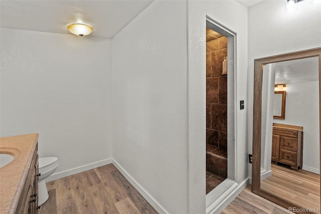 9765LAPINTURAPT La Pintura Pt, Fountain, CO 80817 - bathroom featuring vanity, a tile shower, toilet, wood finished floors, and baseboards