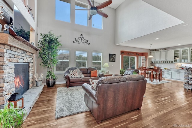 living room with hardwood / wood-style flooring, ceiling fan, a wealth of natural light, and a fireplace