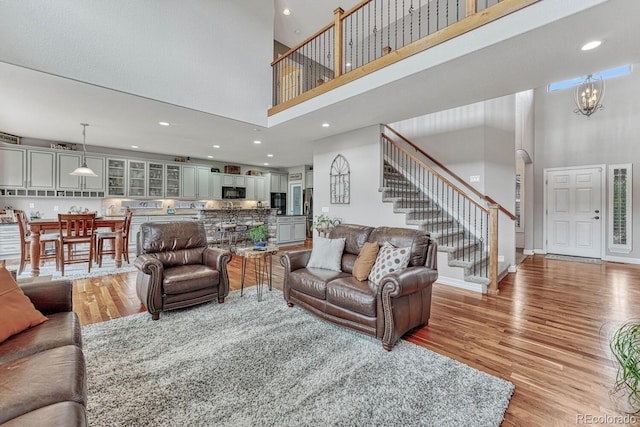 living room with a towering ceiling, an inviting chandelier, and light hardwood / wood-style flooring