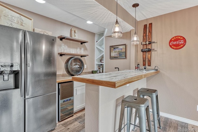 kitchen featuring stainless steel fridge with ice dispenser, butcher block countertops, white cabinetry, a kitchen bar, and kitchen peninsula