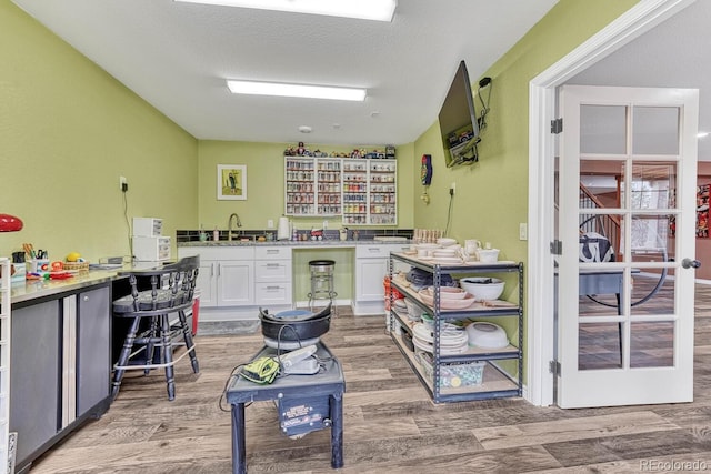 kitchen with sink, hardwood / wood-style flooring, a textured ceiling, and white cabinets