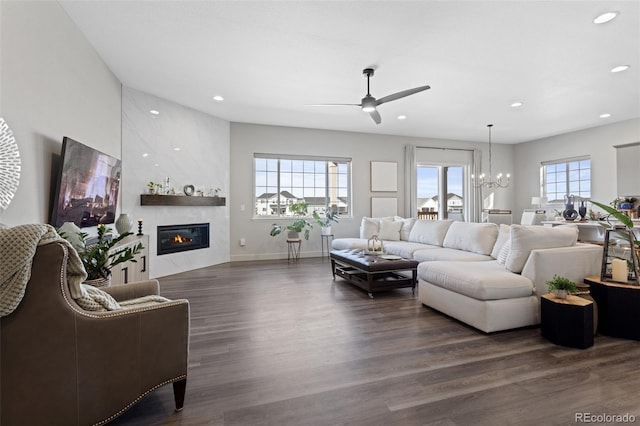 living room featuring ceiling fan with notable chandelier, dark hardwood / wood-style flooring, and a fireplace