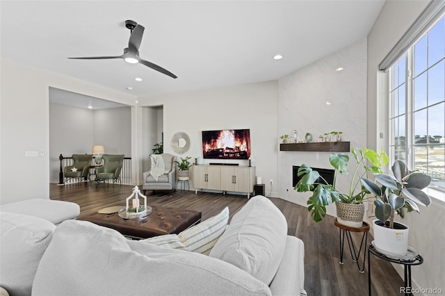 living room featuring ceiling fan, dark hardwood / wood-style floors, and a fireplace