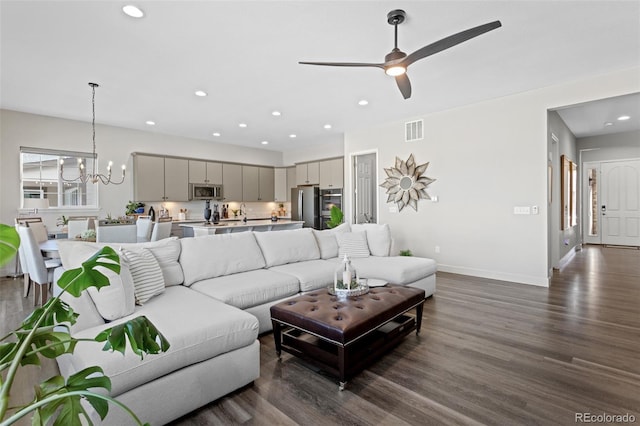 living room with dark hardwood / wood-style floors and ceiling fan with notable chandelier