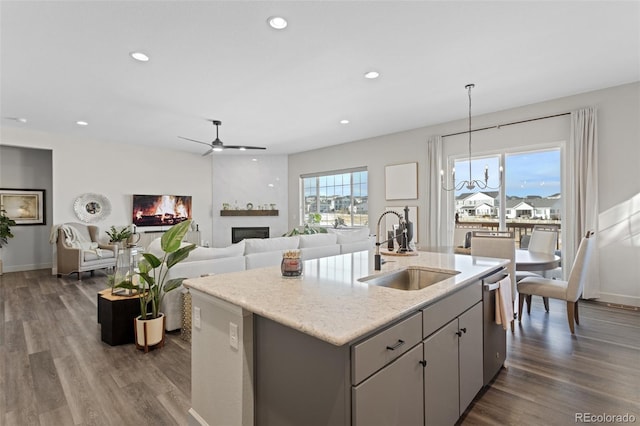 kitchen featuring gray cabinets, an island with sink, pendant lighting, stainless steel dishwasher, and sink