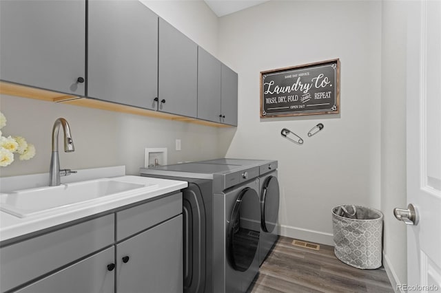 laundry area featuring washer and clothes dryer, dark wood-type flooring, sink, and cabinets