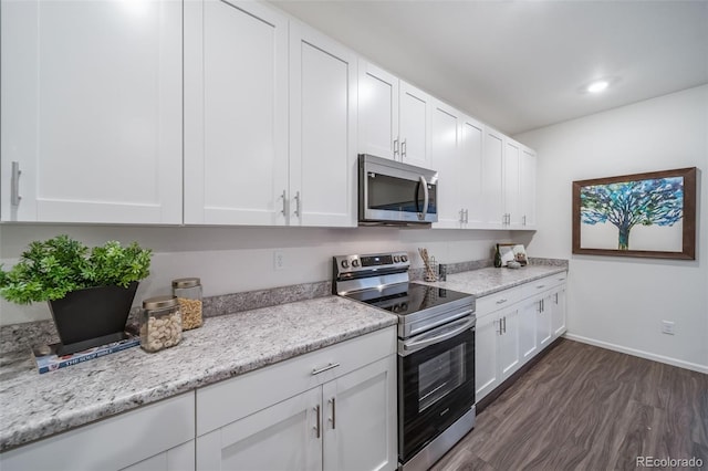 kitchen featuring dark wood-type flooring, appliances with stainless steel finishes, white cabinets, and light stone countertops