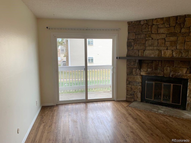 unfurnished living room featuring wood-type flooring, a fireplace, and a textured ceiling