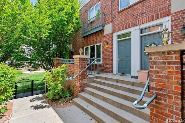 view of exterior entry featuring a gate and brick siding