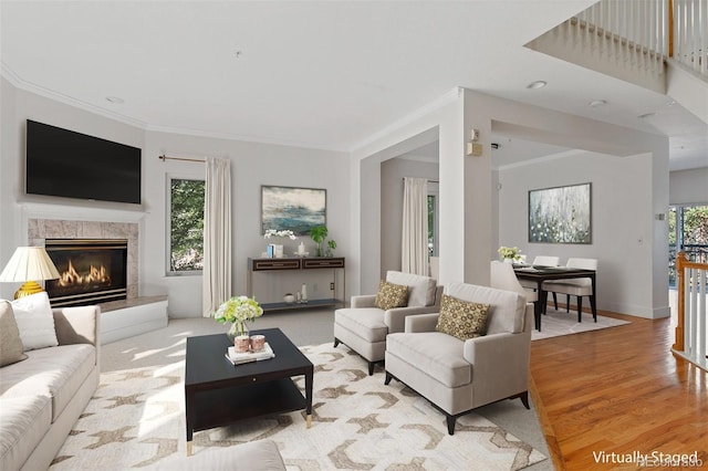 living room with baseboards, ornamental molding, light wood-style flooring, and a fireplace